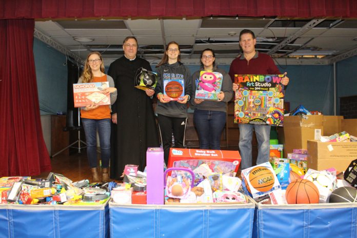 Students from Mount Saint Mary College’s campus ministry program delivered more than 700 toys to Catholic Charities of Orange, Sullivan, and Ulster. The toys were donated by students, staff, and faculty and will be distributed to children in need throughout Catholic Charities’ service area. Pictured in front of the mountain of donated toys are Melody Sarno, Assistant Director of Campus Ministry, Fr Gregoire Fluet, Chaplain & Director of Campus Ministry, MSMC students Amanda Daigle and Alyssa Picard, and Michael Peters, Resource Exchange Coordinator for Catholic Charities.
