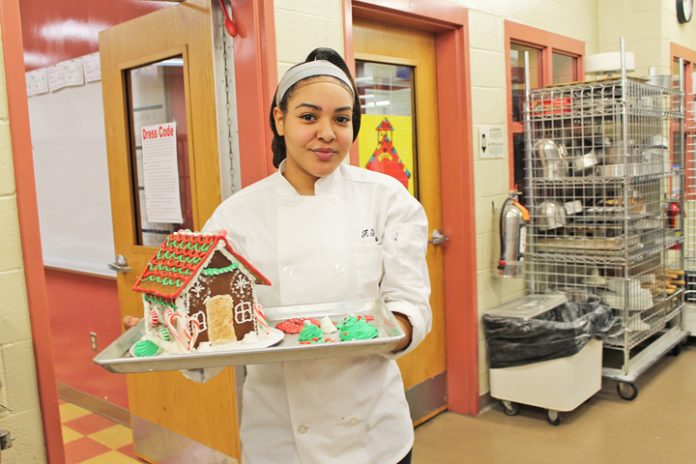 Culinary Arts student Faith Thomas from the Kingston City School District shows off the gingerbread houses her class made for a raffle. Proceeds from the raffle will go to Toys for Tots. Photo: Tammy Cilione