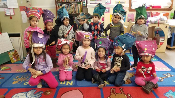 Students at RECAP Head Start in Scotchtown celebrate a study on clothing with hats made of paper shopping bags.