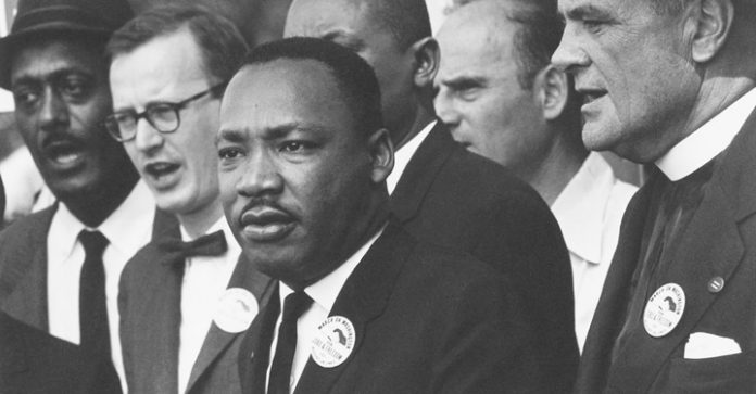 Dr. Martin Luther King Jr. is surrounded by Black and White people during the Poor People’s Movement.