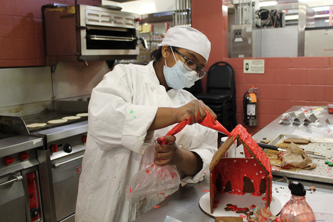Kingston City School District student Alyviah Lewis, who is in the Ulster BOCES Culinary Arts program, decorates a gingerbread airplane hangar.