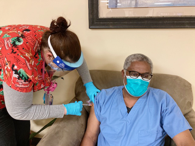 Dr. Alban Burke (right), Chief of Dentistry at Cornerstone Family Healthcare, receives his first dose of the new Moderna COVID-19 vaccine from Nicole Harris (left), an LPN Clinical Coordinator at the facility. Burke was among one of 60 selected staff members to get an initial dose of the vaccine last Wednesday afternoon.