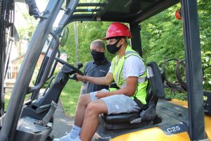 Ulster BOCES Motorcycle/Outdoor Power/Turf Management student Andrew Quick (seated), from the Onteora Central School District, practices operating a forklift under the guidance of Partner Rentals Logistics Manager Michael Pistone.