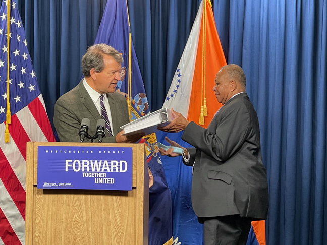 Westchester County Executive George Latimer, left, hands a copy of his 2022 budget to board of legislators’ Chairman Ben Boykin.