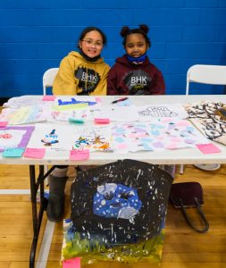 Proud of the art they’ve done, two students from George Washington Elementary present their work at the kick off event at YMCA Kingston.