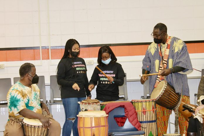 Marlboro High School students Amya White (left) and Glavanah Dumas learn to play along on the drums with the Kofi and Sankofa Drum and Dance Ensemble at the Black History Jamboree on February 28.