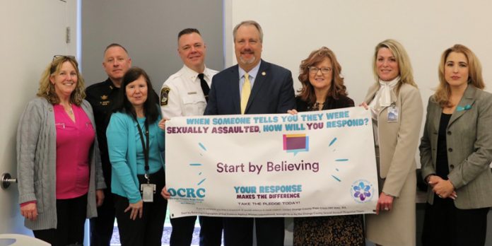 (From left to right) Assistant to the County Executive Mary Pat Smith, Undersheriff Anthony Weed of the Orange County Sheriff’s Office, Angela Jo Henze, Executive Director of MHA, Port Jervis Police Chief William Worden, District Attorney David Hoovler, County Clerk Kelly Eskew, Darcie Miller, Orange County Commissioner of Mental Health and Social Services and Kellyan Kostyal-Larrier, Executive Director of Fearless!, at the Start by Believing Day event at on Wednesday, April 6 at the Orange County Emergency Services Center in Goshen.