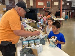 Vincent Serrano, part of the Marine Corp League Det 249 as well as Toys for Tots, explains to some young guests how a toy works at last Monday’s Summer Toy Giveaway.