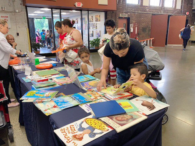 An excited reader guest at last Monday’s Toy Giveaway looks over one of the free books provided by Cornerstone Family Healthcare.
