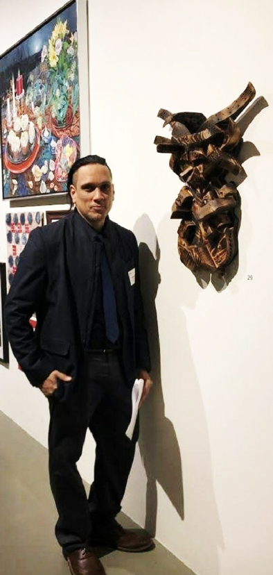 Jose Gonzalez-Soto and his artworks are diverse in size and medium. Jose Gonzalez-Soto poses next to artwork, sculpture entitled “Cultural Transfers”.