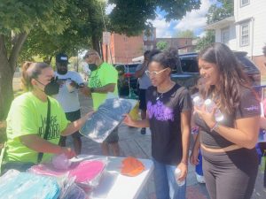 On left, a We are Newburgh volunteer hands a book bag to Iyana Lynch as her friend, Liz Prada looks on. The two soon- to-be Newburgh Free Academy Main Campus juniors were excited to be at Saturday’s back-to-school event.