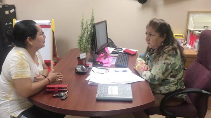 Maria Portilla, seen here on the right, chats with a client in her Greenburgh office at the Town Hall, where she volunteers each Tuesday from 12-5, assisting the Hispanic community with their needs.