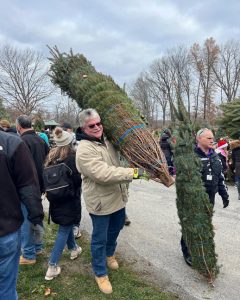 Legislator Kevin Hines carries a tree at the Trees for Troops event at Farmside Acres.