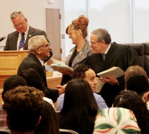 Orange County Court Judge Craig Brown welcomes a new citizen at Wednesday’s naturalization ceremony at the Government Center. In the background is County Clerk Kelly Eskew. At the podium, is Deputy County Clerk James McGee.