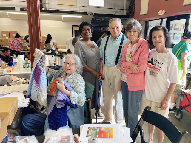 Friday, the very- well attended Giving Day once again took place at the Newburgh Armory Unity Cente. Bill Kaplan, made a surprise appearance, surrounded by several volunteers as well as Giving Day Director, Marietta Allen, seated and displaying one of the beautiful donated blankets available.