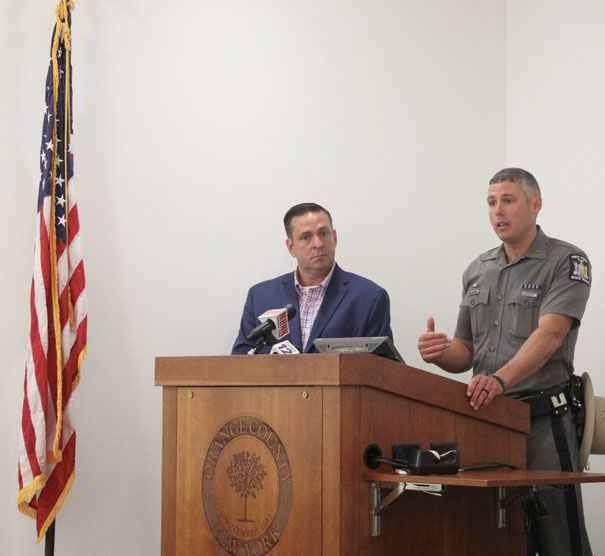 County Executive Steven M. Neuhaus looks on as State Police Captain Peter Cirigliano II speaks during a news conference in June of this year at the County’s Emergency Services Center.
