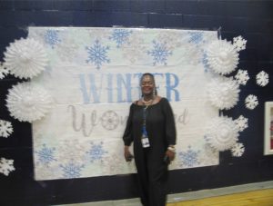 Poughkeepsie Middle School 7th Grade Assistant Principal Felicia Schinella poses in front of a Winter Wonderland poster hung in the school’s gymnasium.