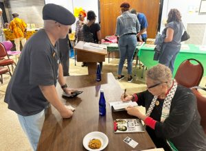 Dr. Rosemari Mealy autographs her book Fidel & Malcolm X: Memories of a Meeting at Malcolm X's 100th Birthday Celebration.