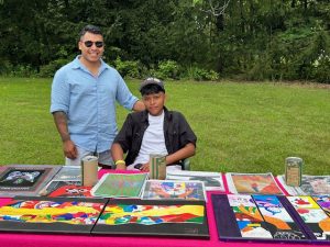 On left, Wilmer Jimenez, Chief Program Officer for Rural Migrant Ministries and co-host of the Voices of Hope concert with youth participant, Samuel Martinez, a rising junior at Newburgh Free Academy, Main Campus, who was overseeing art on display from one of the programs.