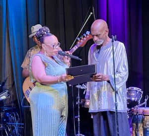 Evangelist Christal Banks presents percussionist Jeff Haynes with a certificate of appreciation at the album debut concert of “Real Gospel in Music According to Jazz,” the new album from BTMOG & Associates.