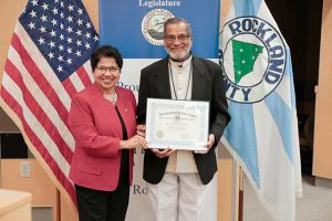 Rockland County legislature Vice Chair Dr. Aney Paul presents the Distinguished Service Award to Fr. Mathew Thomas in recognition of his many contributions to the community.