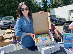 Ashley Collazo, Director of the Mount Saint Mary College Desmond Center, one of the sponsors at Saturday’s Back- to- School event, displays the boxed item, loaded with school supplies- pencil box case, composition box, markers, scissors, erasers, glue and folders, her organization was giving away to guests.
