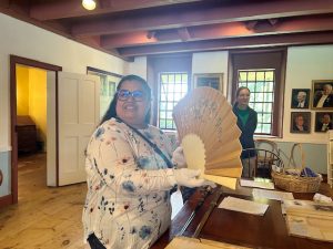 Andrea Montanez of Walden, who was celebrating her birthday, handles the ivory, hand painted, daisy- decored fan from Tiffany Company, one of several items available at Sunday’s White Gloves event.