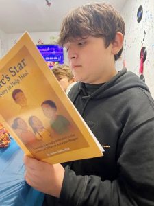 One of the youth on hand at Friday night’s Family-based Youth/Teen Grief & Loss event, is fully absorbed in the book, Marc’s Star, that was signed by author, Jemika Hall, Founder of the non-profit, M.A.R.C.’S. Friends Inc., in memory of her son whose life was senselessly lost to gun violence in 2018.