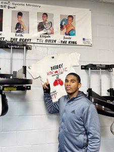 22-year-old Professional Boxer Elijah “The Bully” points to a photo of himself at age 8 with Hook Elite Boxing Club sporting a championship medal and belt.