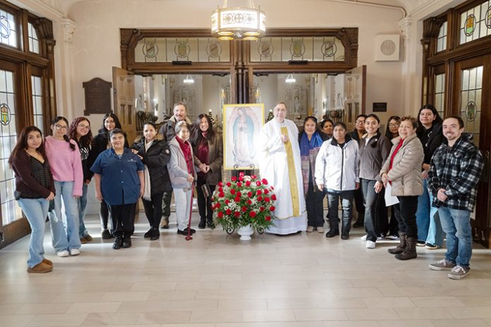 Fr. Gregoire Fluet (center), Vice President for Mission and Ministry at Mount Saint Mary College, joins students and community members around a portrait of Our Lady of Guadalupe, adorned with traditional red roses, during the college’s special Feast Day Mass. Photo by Lee Ferris.