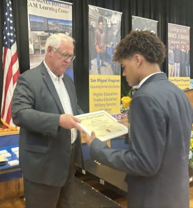 Father Mark hands Micah Fisher his diploma.