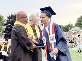 NECSD BOE Member Philip Howard gives graduate some dap after presenting him with his diploma during Newburgh Free Academy's commencement ceremony.