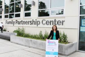 SART Coordinator Kathy Peluso with a "Swap the Shame, Shift the Blame" poster outside of the Family Partnership Center.