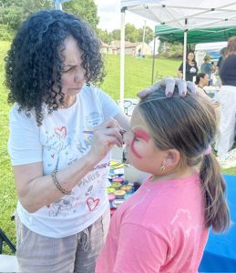 Employees from Sun River Health, the Title Sponsor for the event, provide face painting fun for young guests Saturday.